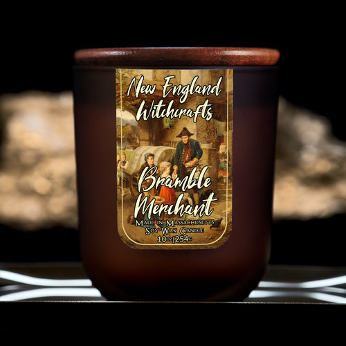 Image depicts a frosted amber candle jar with lid and a label depicting an oil painting of a merchant arriving in town surrounded by curious children.