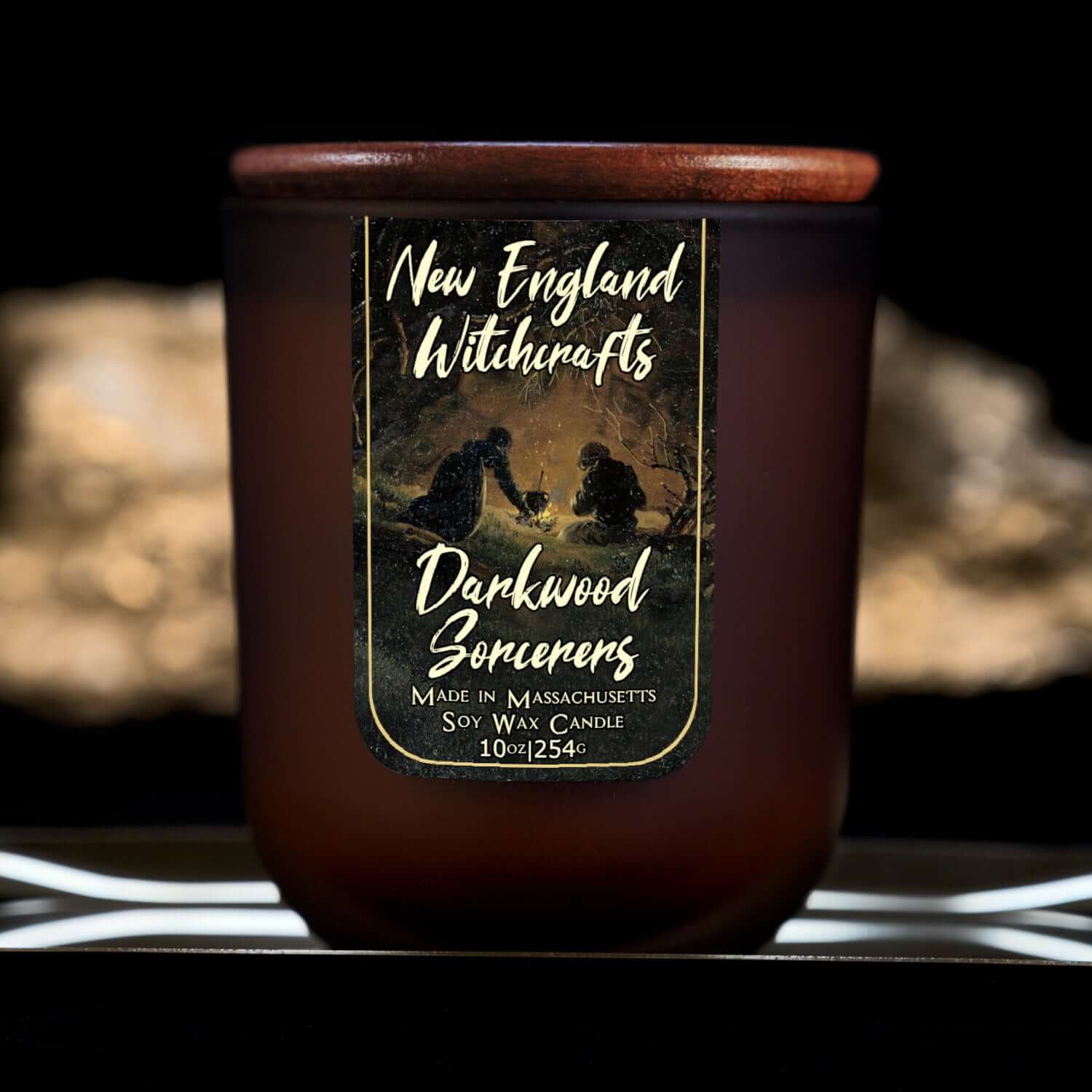 Image depicts a frosted amber candle jar with lid and a label depicting an oil painting of sorcerers conjuring in secret in the forest.