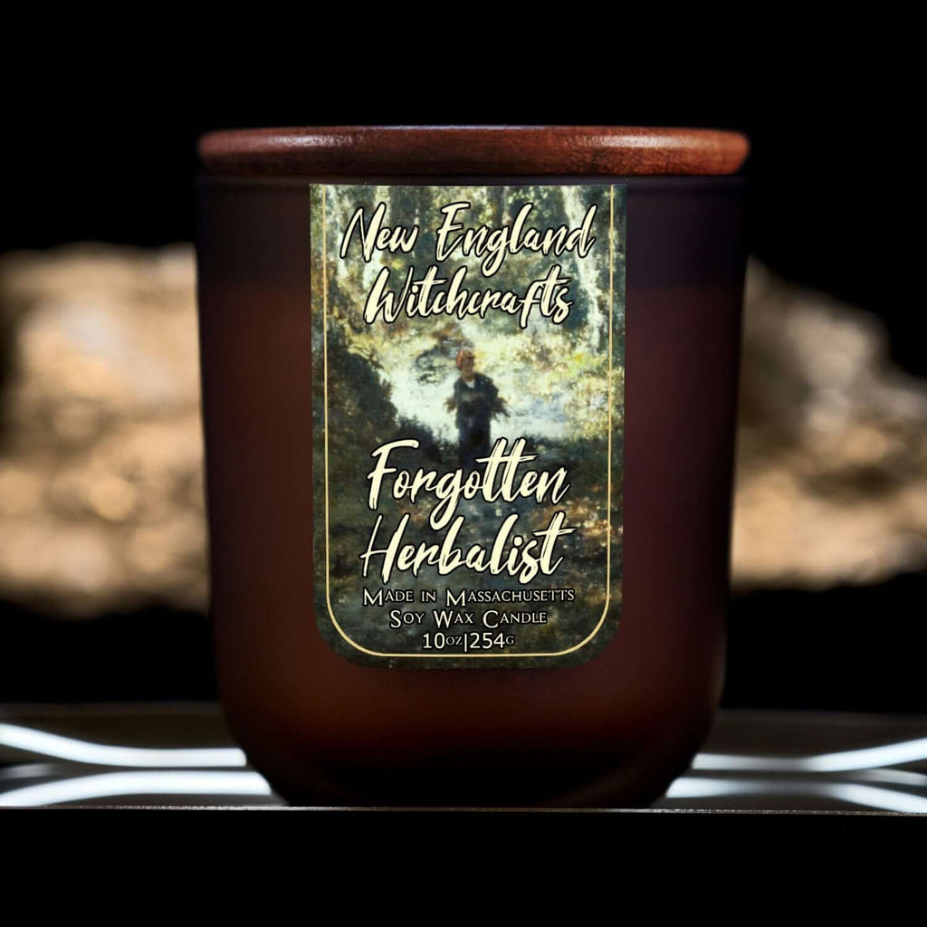 Image depicts a frosted amber candle jar with lid and a label depicting an oil painting of a lone woodsman in the distance.