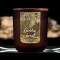 Image depicts a frosted amber candle jar with lid and a label depicting an oil painting of a hermit sleeping against his shed.