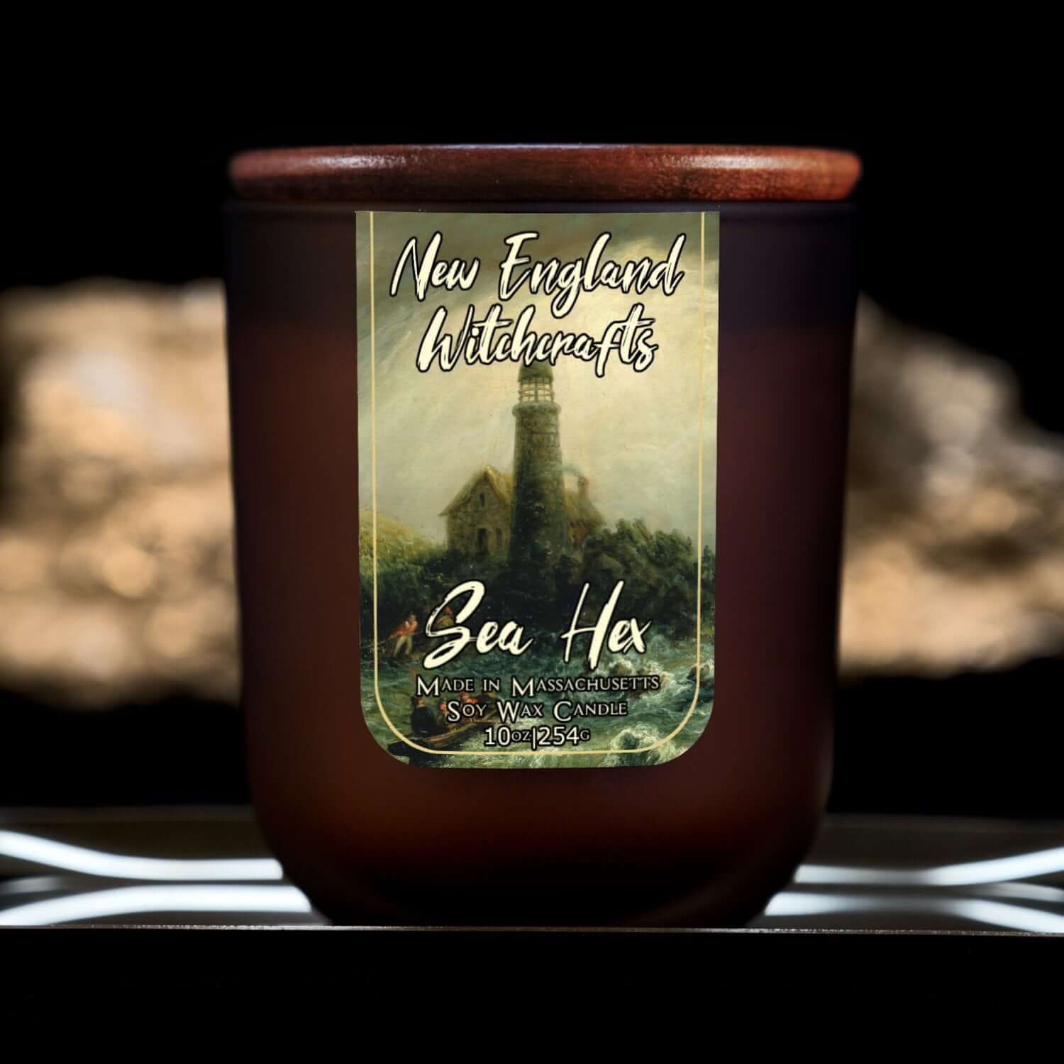 Image depicts a frosted amber candle jar with lid and a label depicting an oil painting of stormy seas and a lighthouse.