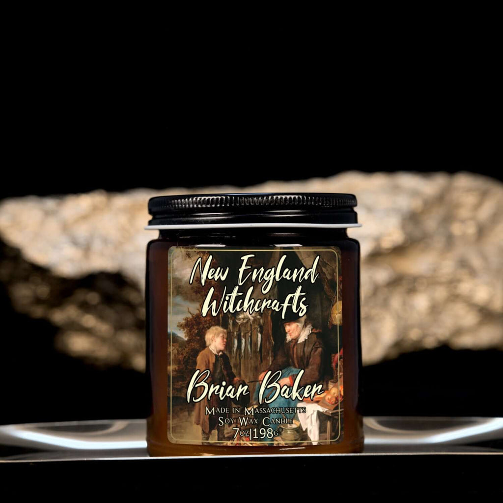 Image depicts an amber candle with black lid, smaller, and a label depicting an oil painting of a child conversing with an old baker woman.