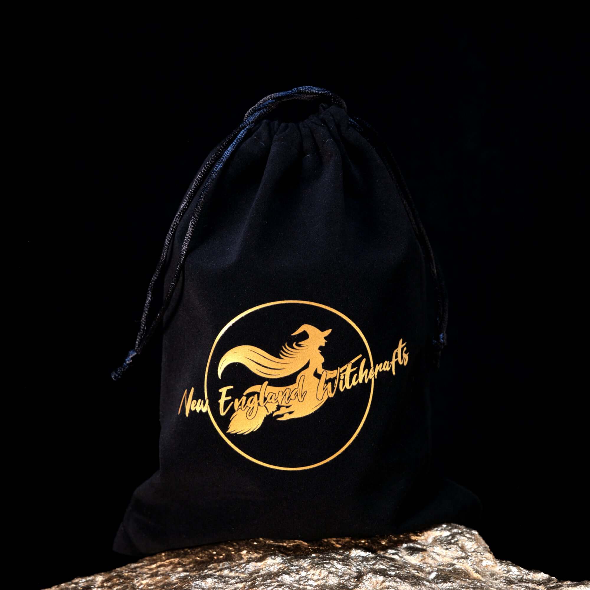 Image depicts a black velvet bag with witch logo in gold and the words New England Witchcrafts